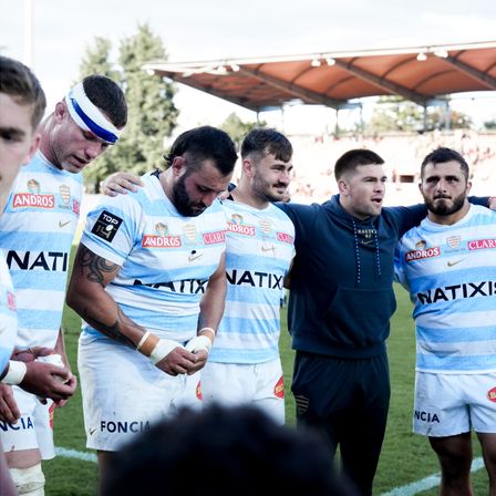 Les joueurs du Racing 92, en cercle, se tenant par les épaules lors d’une réuinon d’équipe pendant un match de rugby.