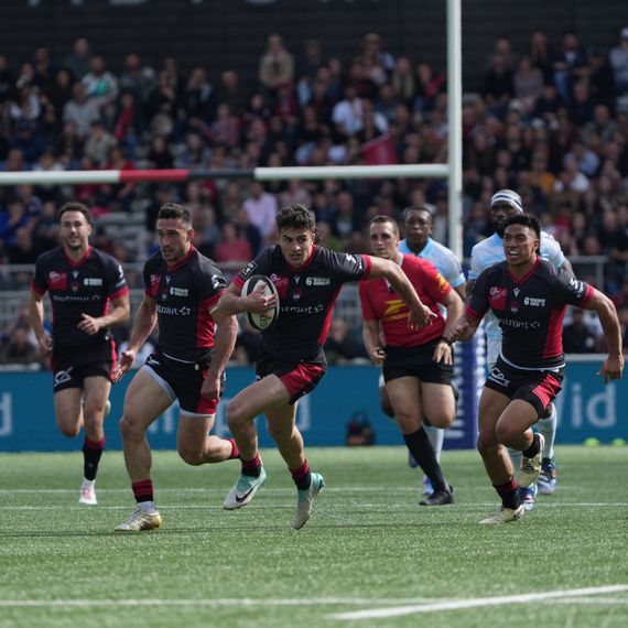 Des joueurs du LOU Rugby en train de courir pour marquer un essai.