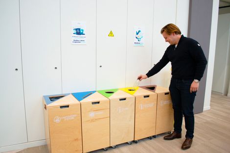 Homme mettant une bouteille dans une poubelle de recyclage.